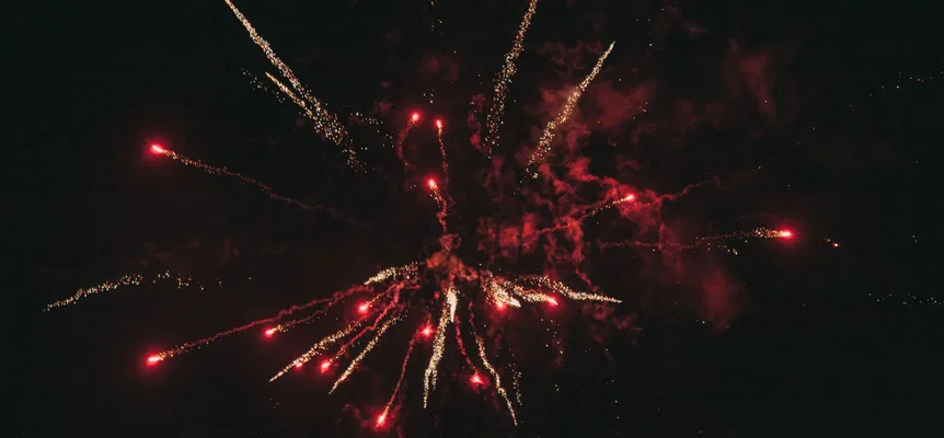 Des traînées de feu d'artifice rouges et dorées qui éclatent sur un ciel de nuit noir