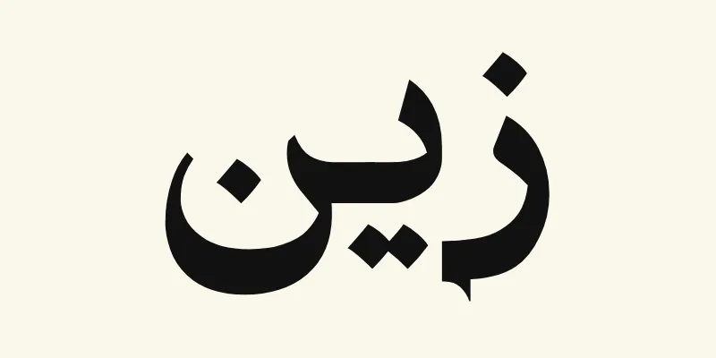 Le prénom Zayn en arabe, زين, en lettres de titrage noires à petites terminaisons pointues de la police Katibeh, sur fond crème